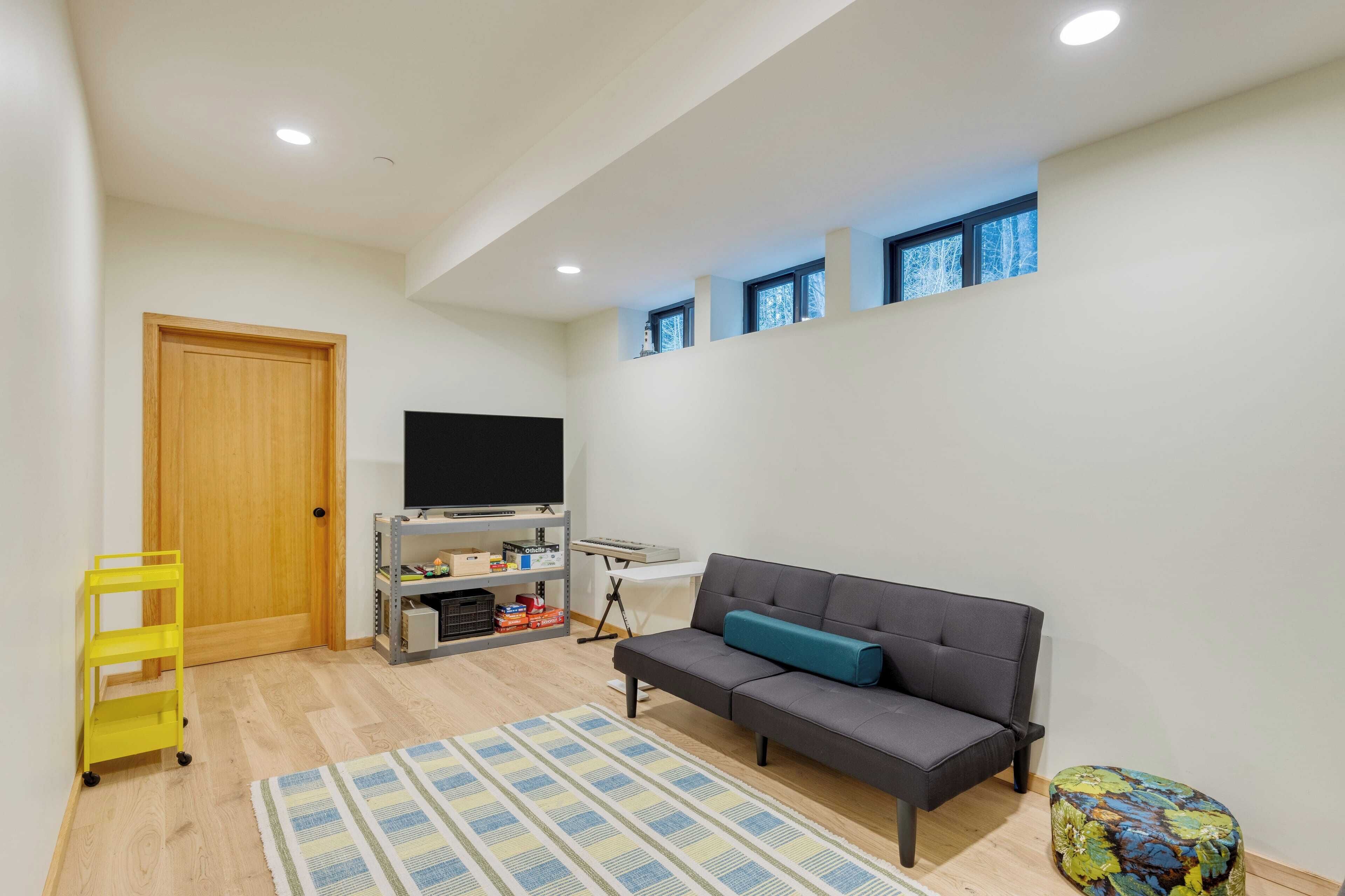 A modern living room with a sofa, a TV, a wooden door, and a small table.