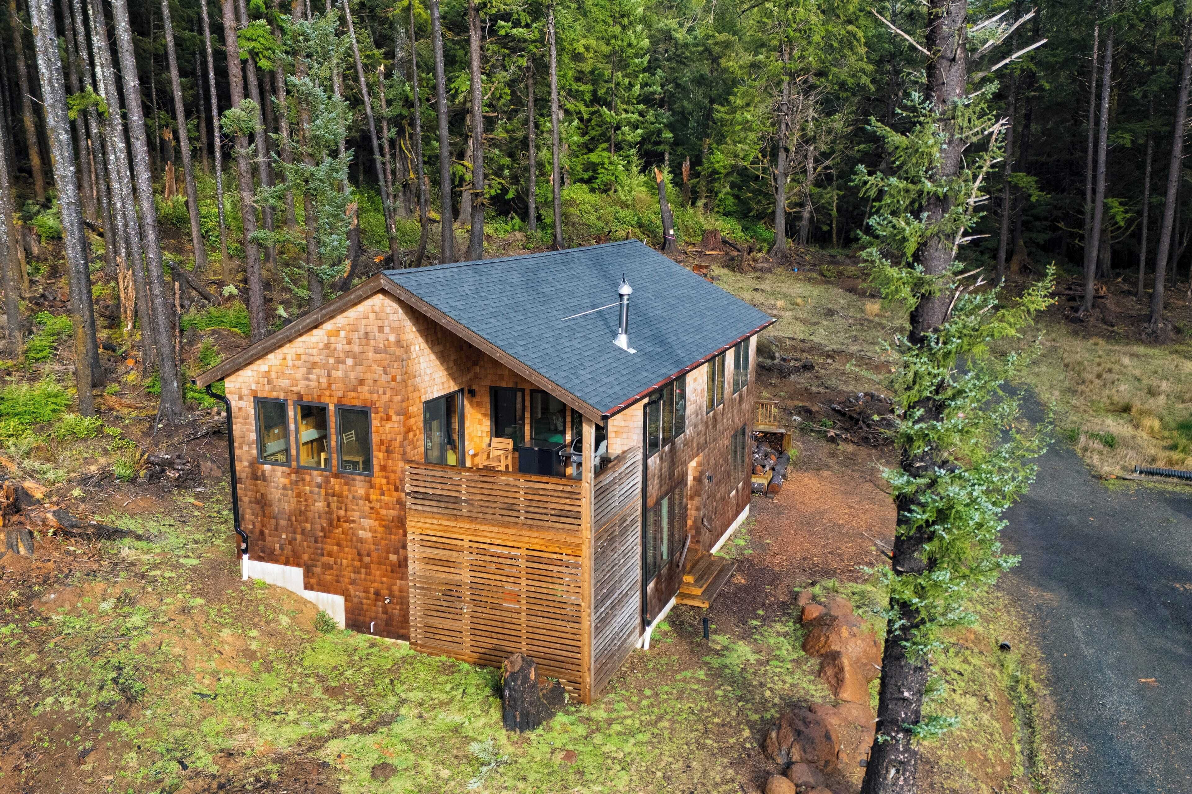 A small wooden cabin with a sloped roof, a chimney, and a windowed front porch.