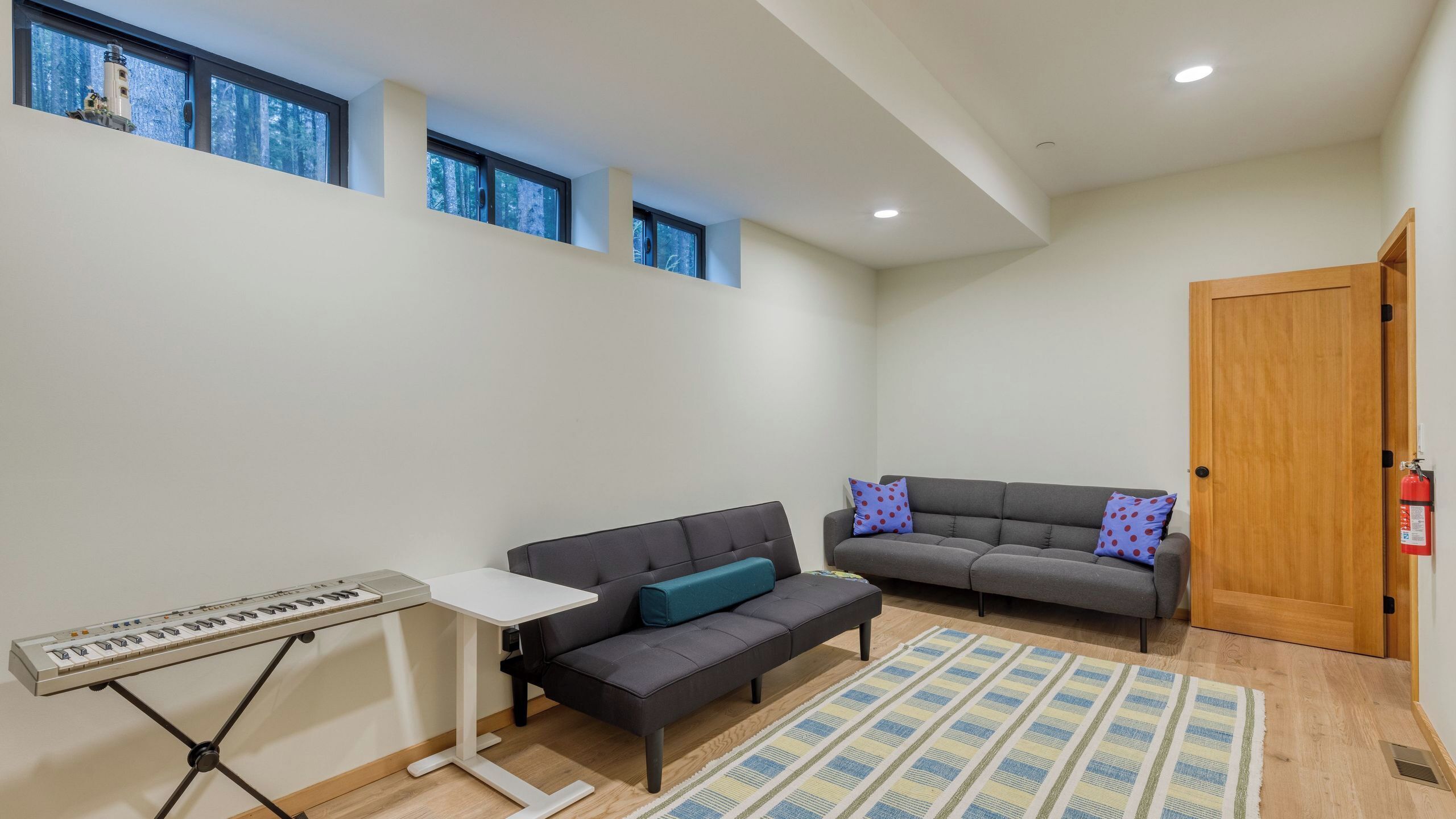 A modern living room with a gray sofa, a white table with a keyboard, and a patterned rug.