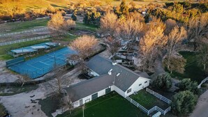 An aerial view of a rural property with a tennis court, a white building, and surrounding fields. - Victorian Manor In Paso Robles Wine Country + Pool, Hot Tub, Firepit, Tennis Court Sleeps 28 (Paso Robles)