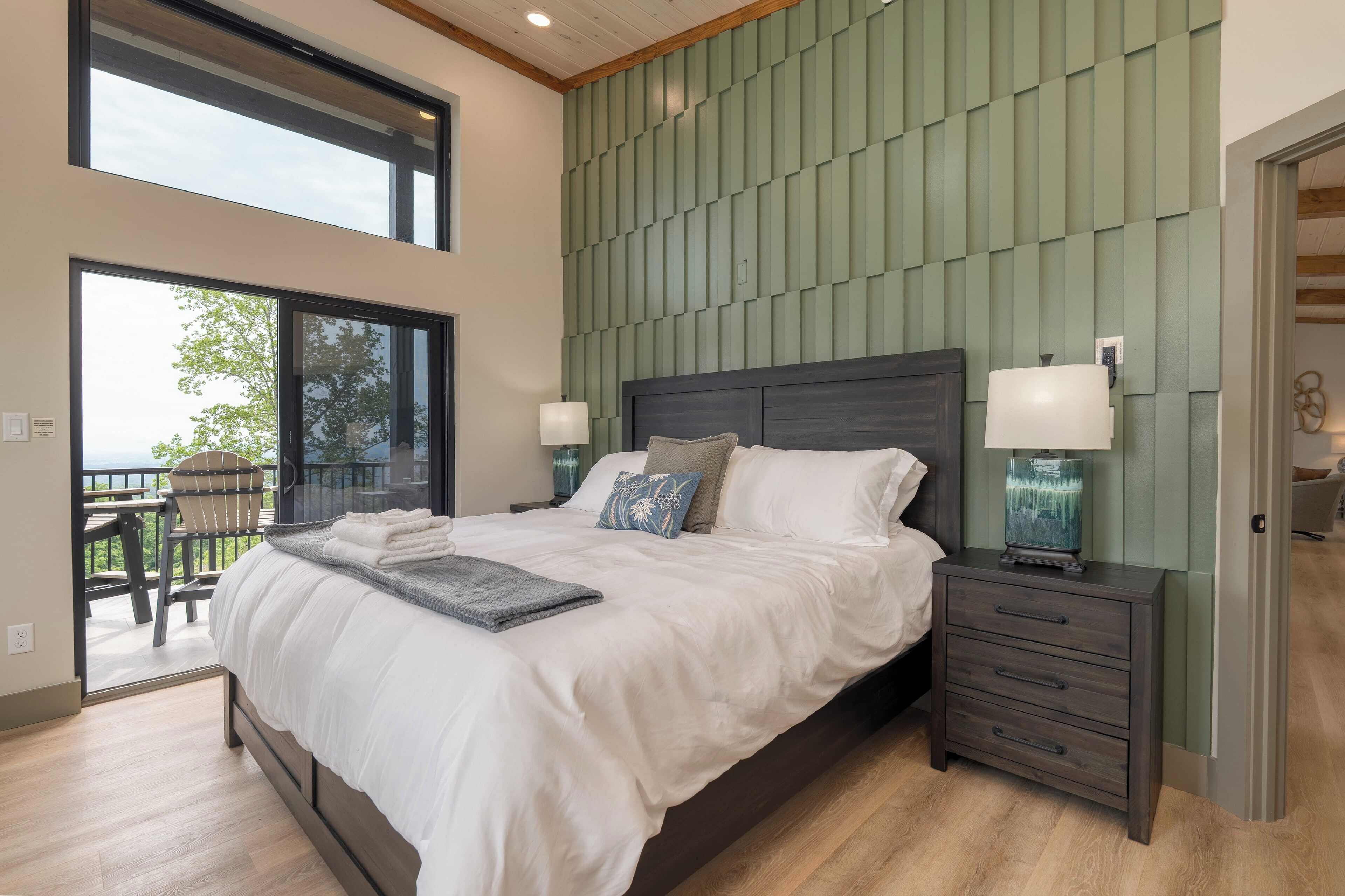A bedroom with a large bed, two bedside tables, a view to the outside, and a green acoustic panel wall.