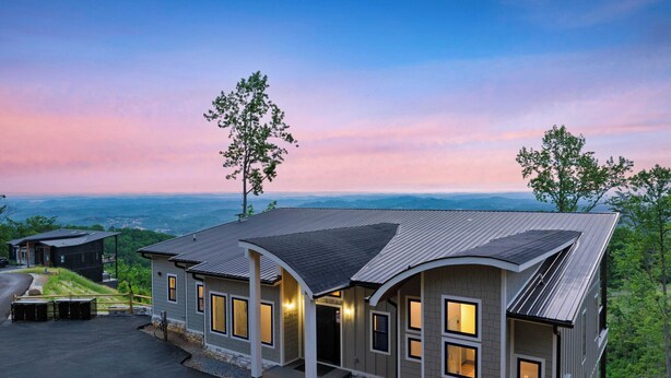 A modern house with a curved roof, large windows, and a view of the surrounding landscape. - Grand Vista Retreat Luxury Group Retreat w/ Indoor Pool, Arcade & 56-mile Views (Sevierville)