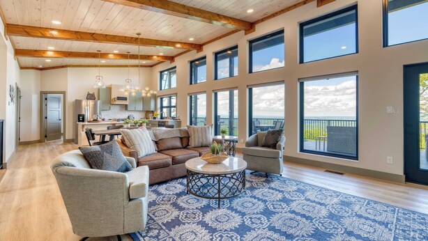 A spacious living area with a large window, a dining area, and a kitchen.