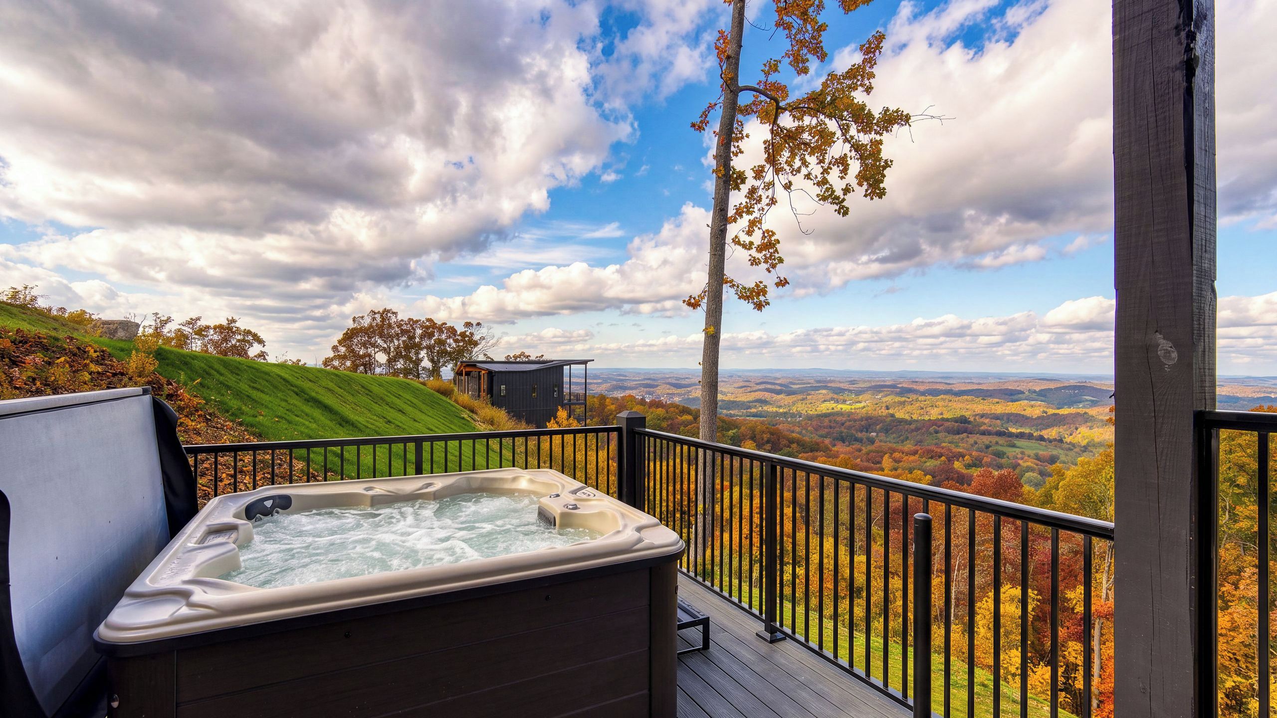 A hot tub on a deck with a scenic view of autumn foliage and a distant landscape.