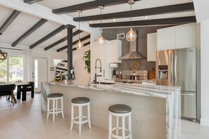 Una cocina moderna con una isla de mármol, electrodomésticos de acero inoxidable e iluminación colgante.
