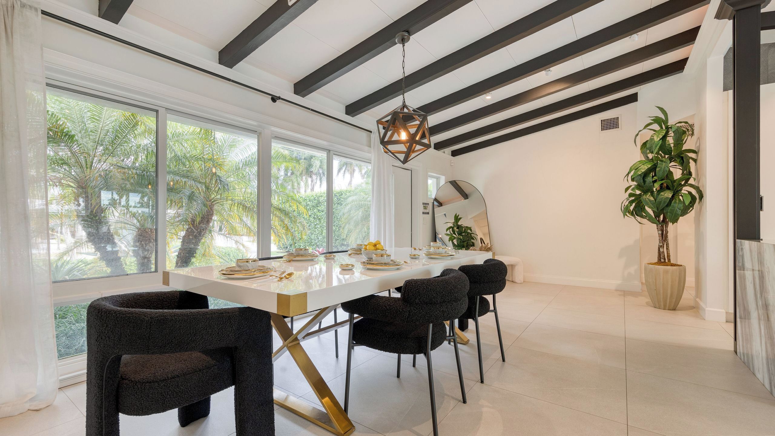 A modern dining area with a long table, black chairs, and a hanging light fixture.