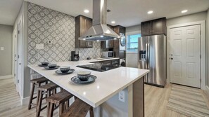 A modern kitchen with a central island, stainless steel appliances, and patterned backsplash. - 2 Condos Beach Access, 2 Pools, Pickleball & Tennis Island Retreat Complex (Port Aransas)