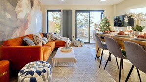 Un soggiorno moderno con divano, tavolino da caffè e zona pranzo con sedie e albero di Natale.