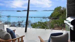 A terrace with a view of a lake and distant islands, furnished with chairs and a grill. - Hidden Cove 2 - 4 Bedroom, 4 Bathrooms, Waterfront with Private Pool and buggy (Hamilton Island)