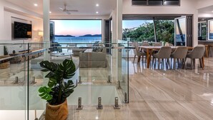 A spacious living area with a glass railing, a large potted plant, and a view of the sea. - Hidden Cove 2 - 4 Bedroom, 4 Bathrooms, Waterfront with Private Pool and buggy (Hamilton Island)