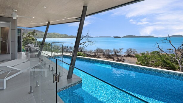 A modern infinity pool with clear blue water, a glass railing, and a view of the ocean and distant islands. - Hidden Cove 2 - 4 Bedroom, 4 Bathrooms, Waterfront with Private Pool and buggy (Hamilton Island)