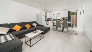 Una sala moderna con un sofá, una mesa de centro y una zona de comedor con sillas.