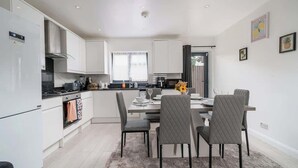 Una cocina moderna con armarios blancos, un comedor con mesa y sillas, y un ventanal.