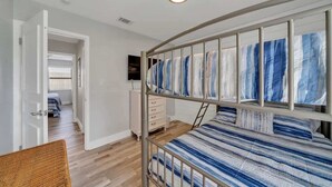 Un dormitorio con una cama nido, una mesita de noche, una silla y un televisor.