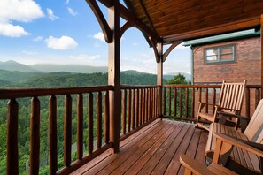 Een houten terras met uitzicht op een bebost berglandschap.