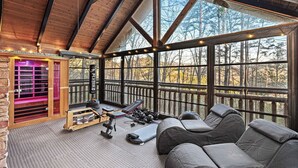 A spacious room with a large window, wooden ceiling beams, a massage chair, and a massage table. - Sleeps 13 | Pet-Friendly, Hot Tub, Sauna & Theater (Sevierville)