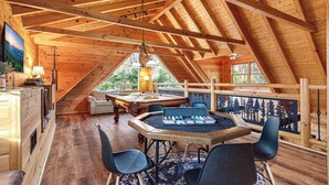 A cozy attic room with a pool table, wooden beams, and a view of the outdoors. - Sleeps 13 | Pet-Friendly, Hot Tub, Sauna & Theater (Sevierville)