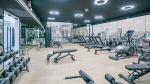 Ein modernes Fitnessstudio mit unterschiedlichen Trainingsgeräten, großen Fenstern und Blick auf die Stadt.