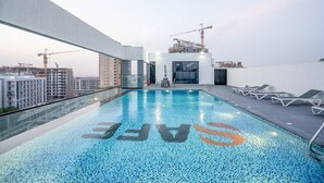Ein Pool auf dem Dach mit freiem Blick auf die Stadtlandschaft und Baukräne im Hintergrund.