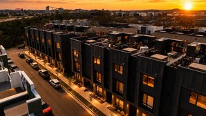 Un edificio moderno de varios pisos, con amplias ventanas y un estacionamiento.