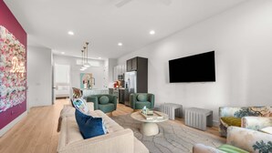 Una sala de estar moderna con un sofá, sillones, una mesa de centro y un televisor de pantalla plana montado en la pared.