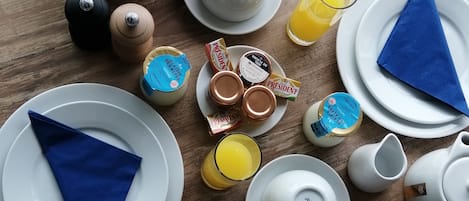 Una mesa de desayuno con cruasanes, pastelería y una variedad de untables y condimentos.