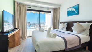 A hotel room with a large bed, a TV, and a view of the marina.
