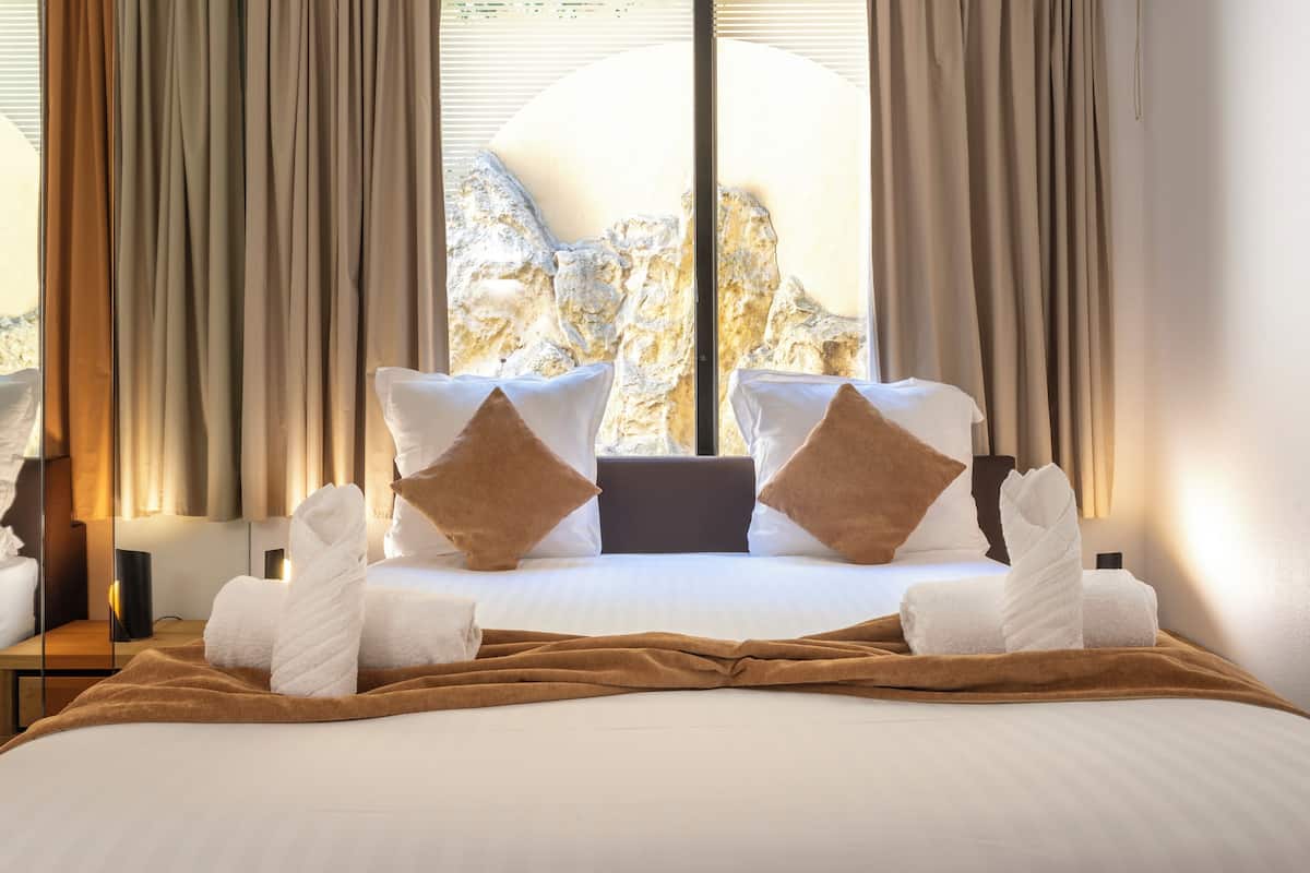 Habitación de hotel con una cama, almohadas y toallas dispuestas sobre ella.