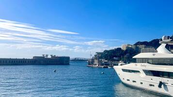 Un puerto deportivo con un yate grande amarrado, un muelle con edificios y un cielo azul despejado.