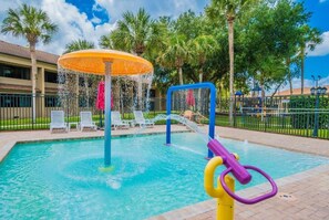 Een buitenzwembad, parasols bij het zwembad en ligstoelen