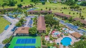 Vista aérea de um resort com várias quadras de tênis, uma piscina e vários edifícios.