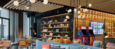 A modern lounge area with a blue sofa, leather chairs, and a bookshelf filled with books and toys.