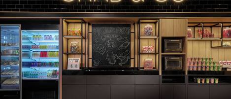 A 'GRAB & GO' snack kiosk with a neon sign, a chalkboard menu, and shelves stocked with snacks and drinks.