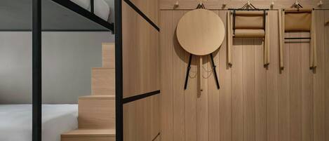 A room with a bunk bed, wooden wardrobe, and a round mirror.