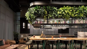 A bar area with a wooden counter, bar stools, and a variety of bottles and glasses. - New Hotel Moxy Montreal Downtown (Montreal)