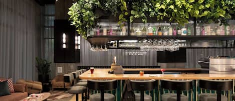 A bar area with a wooden counter, bar stools, and a variety of bottles and glasses.