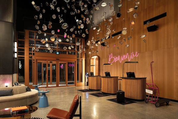 A lobby with a reception desk, a sofa, and a coffee table. - New Hotel Moxy Montreal Downtown (Montreal)