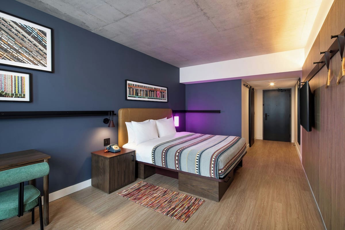 Quarto moderno com cama, mesa de cabeceira e escrivaninha com cadeira.