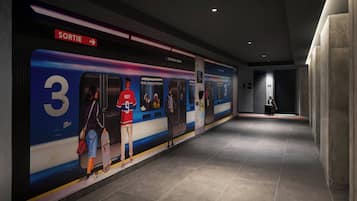 Una estación de metro con andén, tren y señalización que indica la salida.