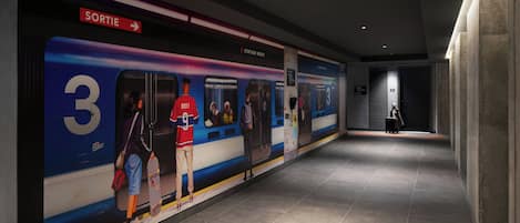 A subway station with a platform, a train, and a sign indicating the exit.