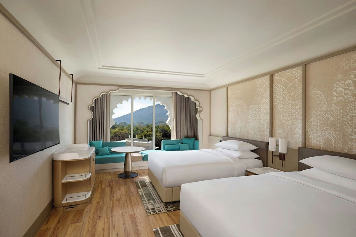 Une chambre d’hôtel avec deux lits, un canapé, une télévision et une vue sur l’extérieur.