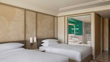 A hotel room with two beds, a large mirror, and a bathroom visible through an open door.
