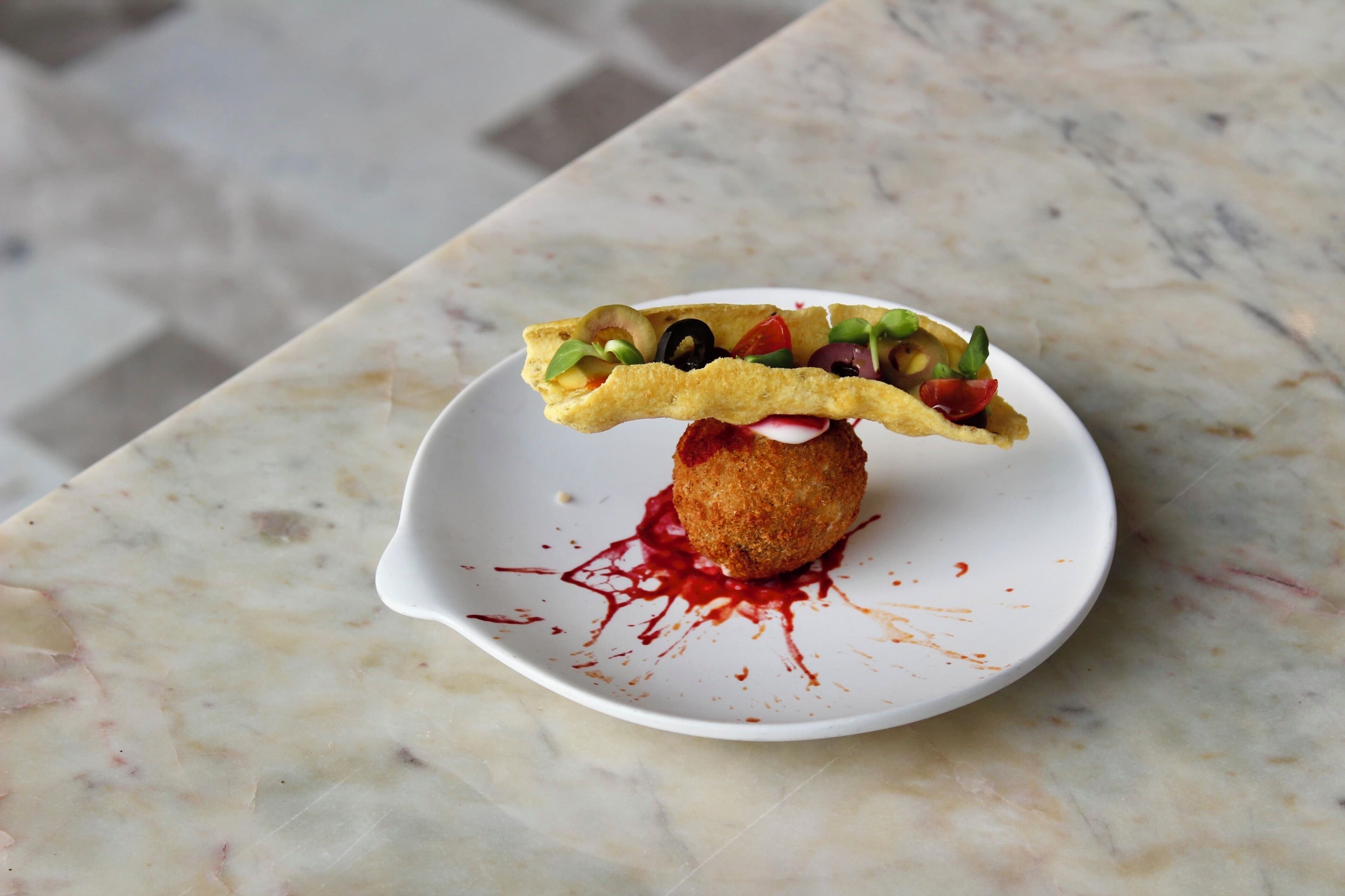 A dish with a crispy base and a colorful topping on a white plate.