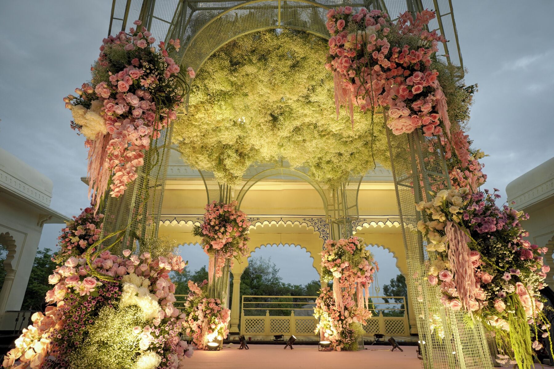 Een bloemrijke boog met een decoratief plafond en een gele balustrade.