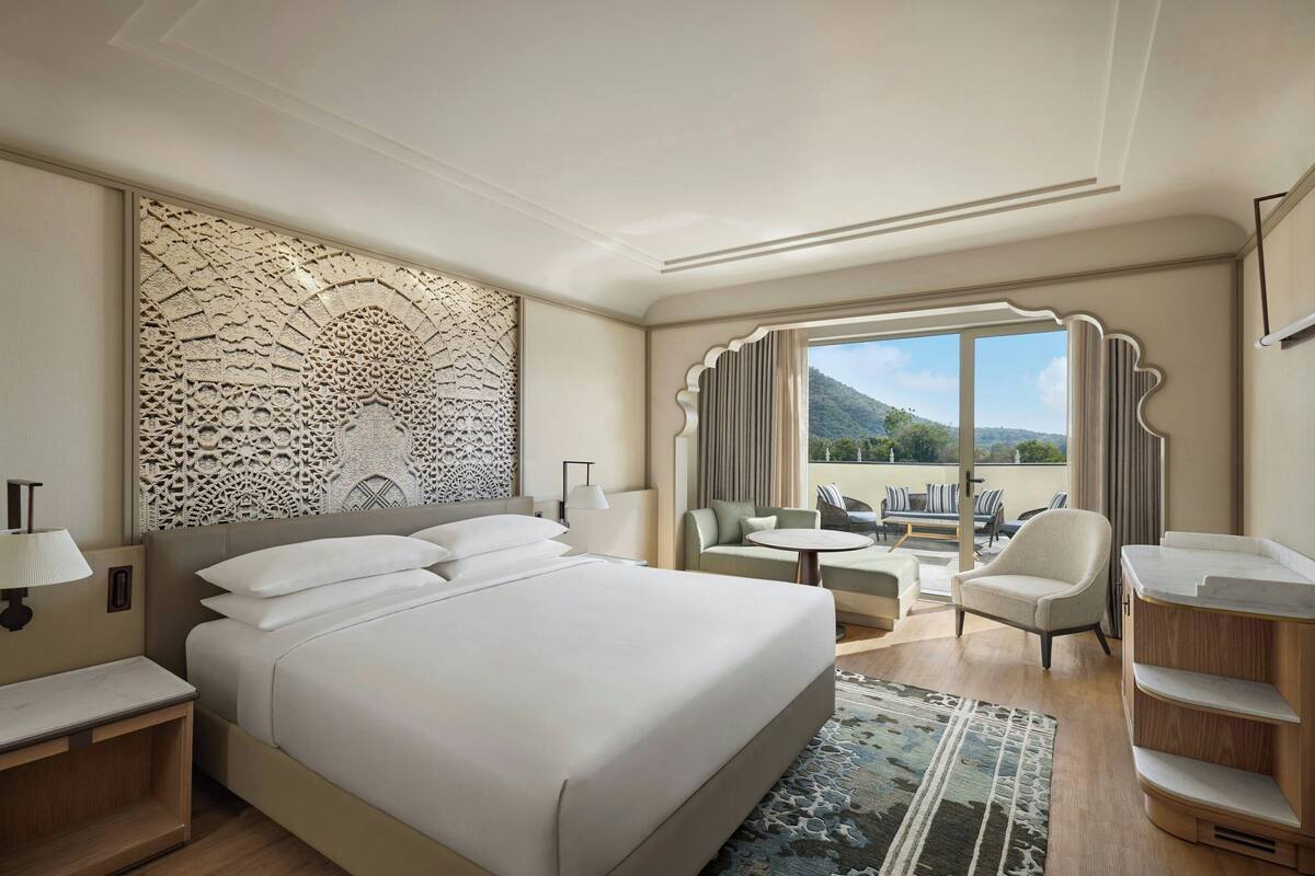 Une chambre d’hôtel dotée d’un grand lit, d’un coin salon avec une table et offrant une vue sur l’extérieur.