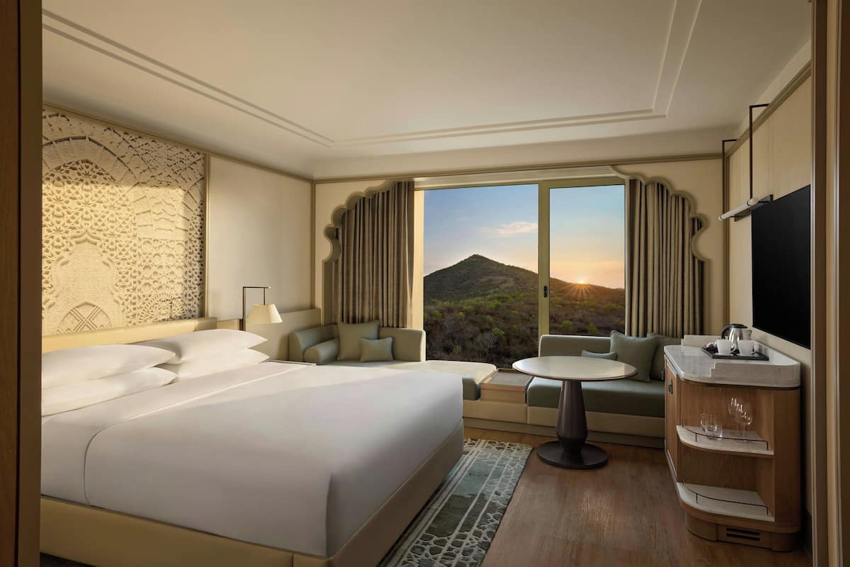 Une chambre d’hôtel avec un grand lit, un canapé, une petite table et une coiffeuse avec un miroir.