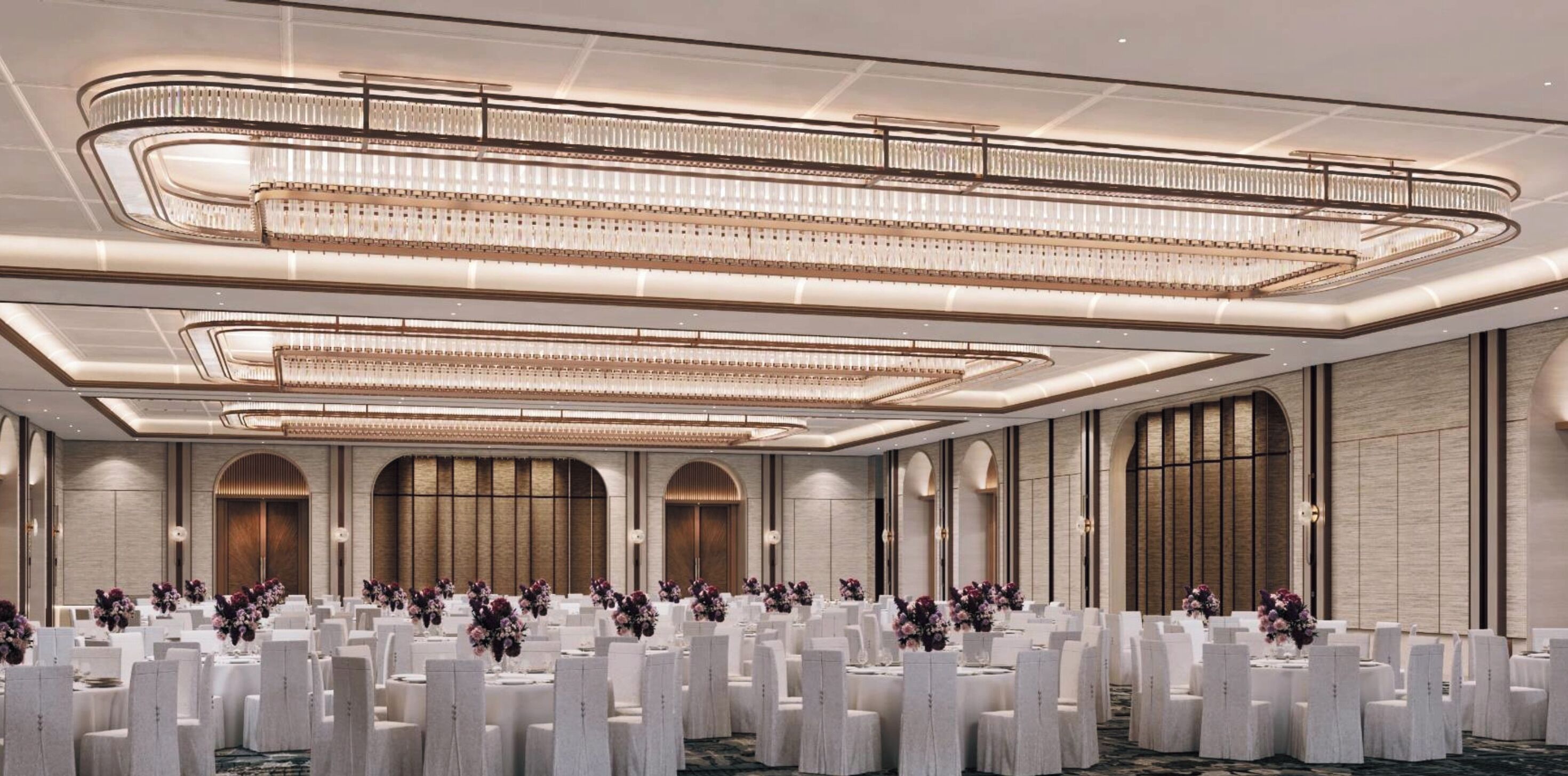 Un amplio salón de banquetes con varias mesas redondas, cada una cubierta con manteles blancos y centros de mesa florales.