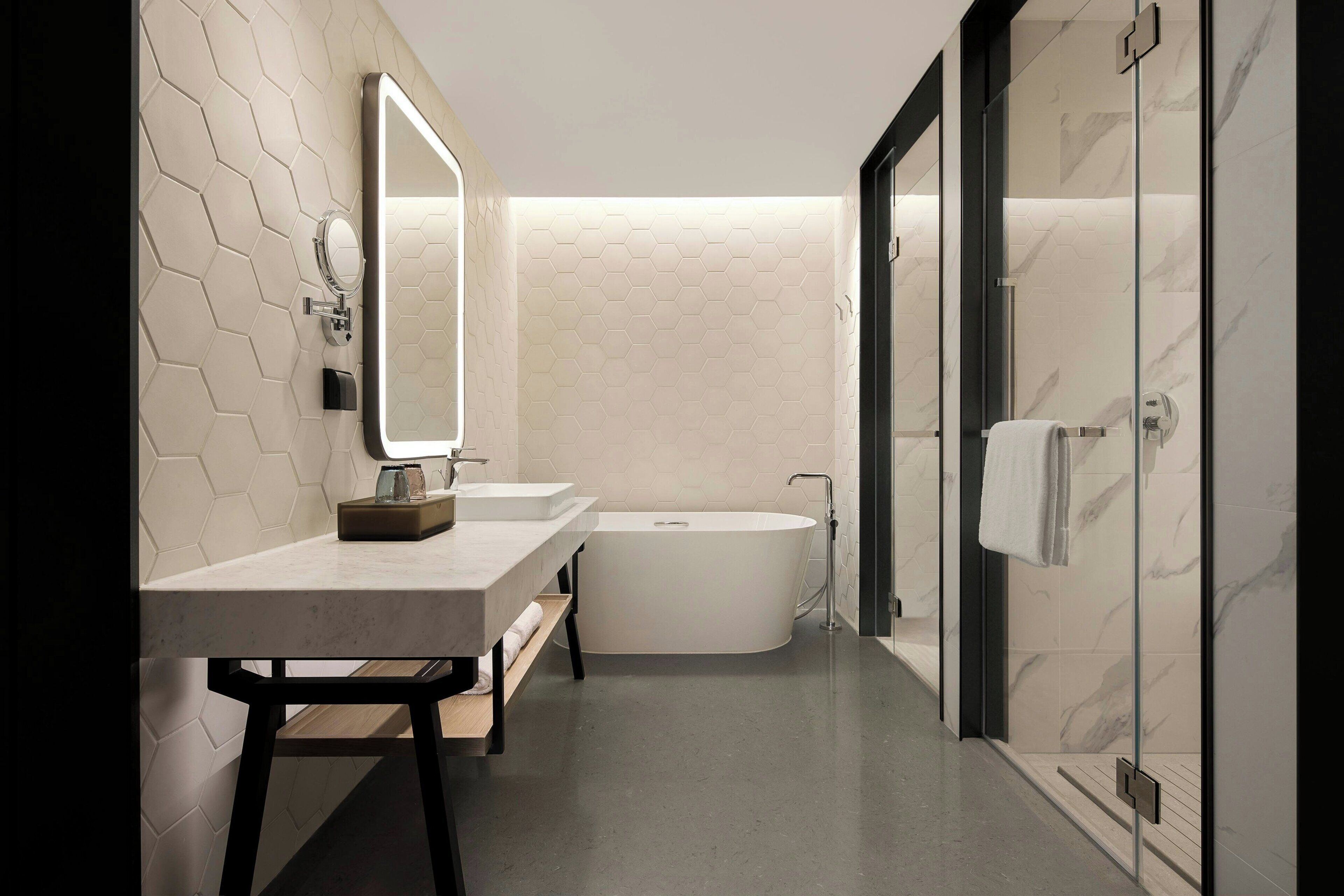 A modern bathroom with a freestanding bathtub, a vanity with a mirror, and a towel rack.