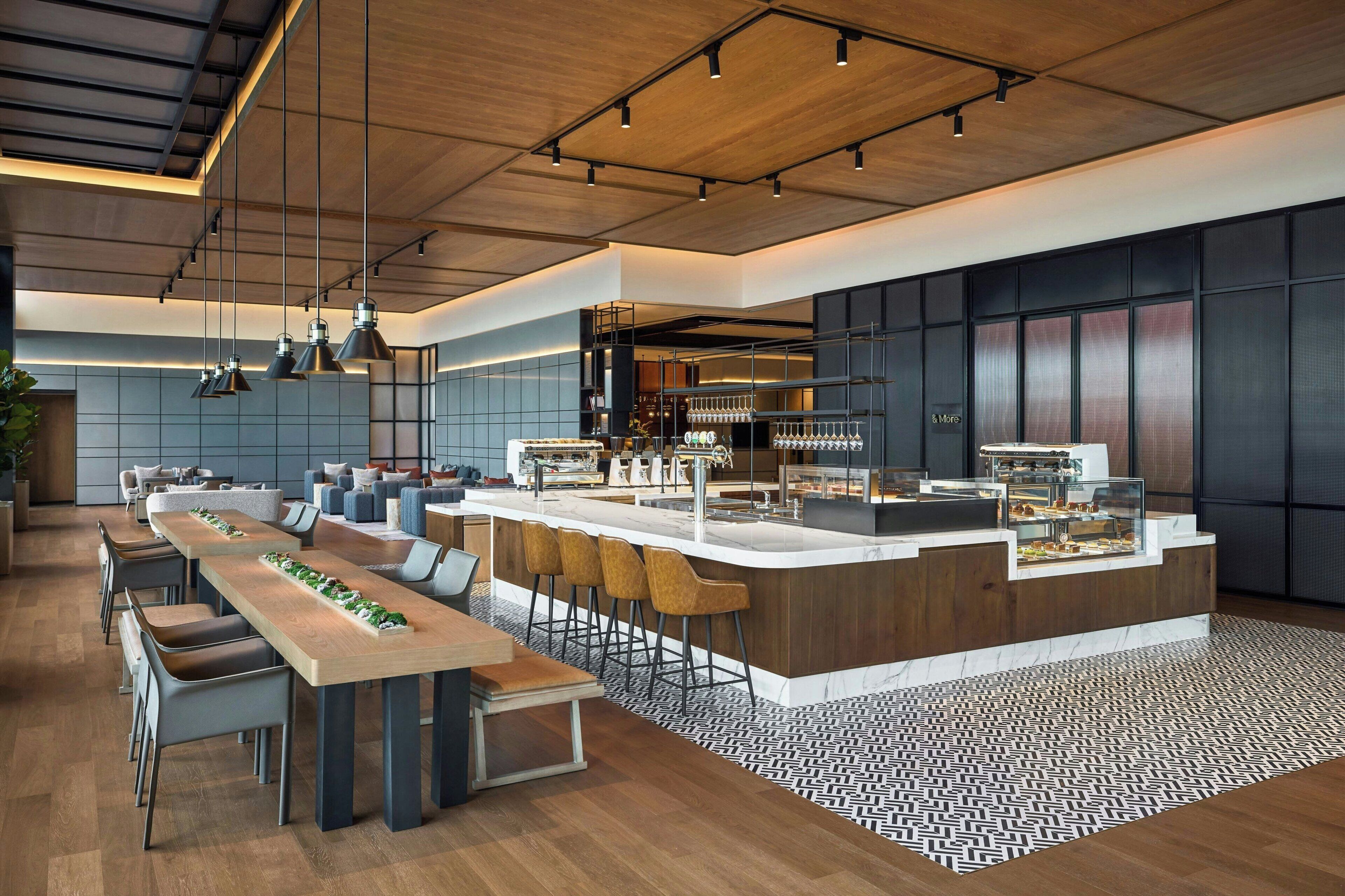 Une cuisine moderne dotée d’un long comptoir, de tabourets de bar et de luminaires suspendus.