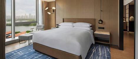 Habitación de hotel moderna con una cama grande, vistas de la ciudad y un balcón con vista al río.